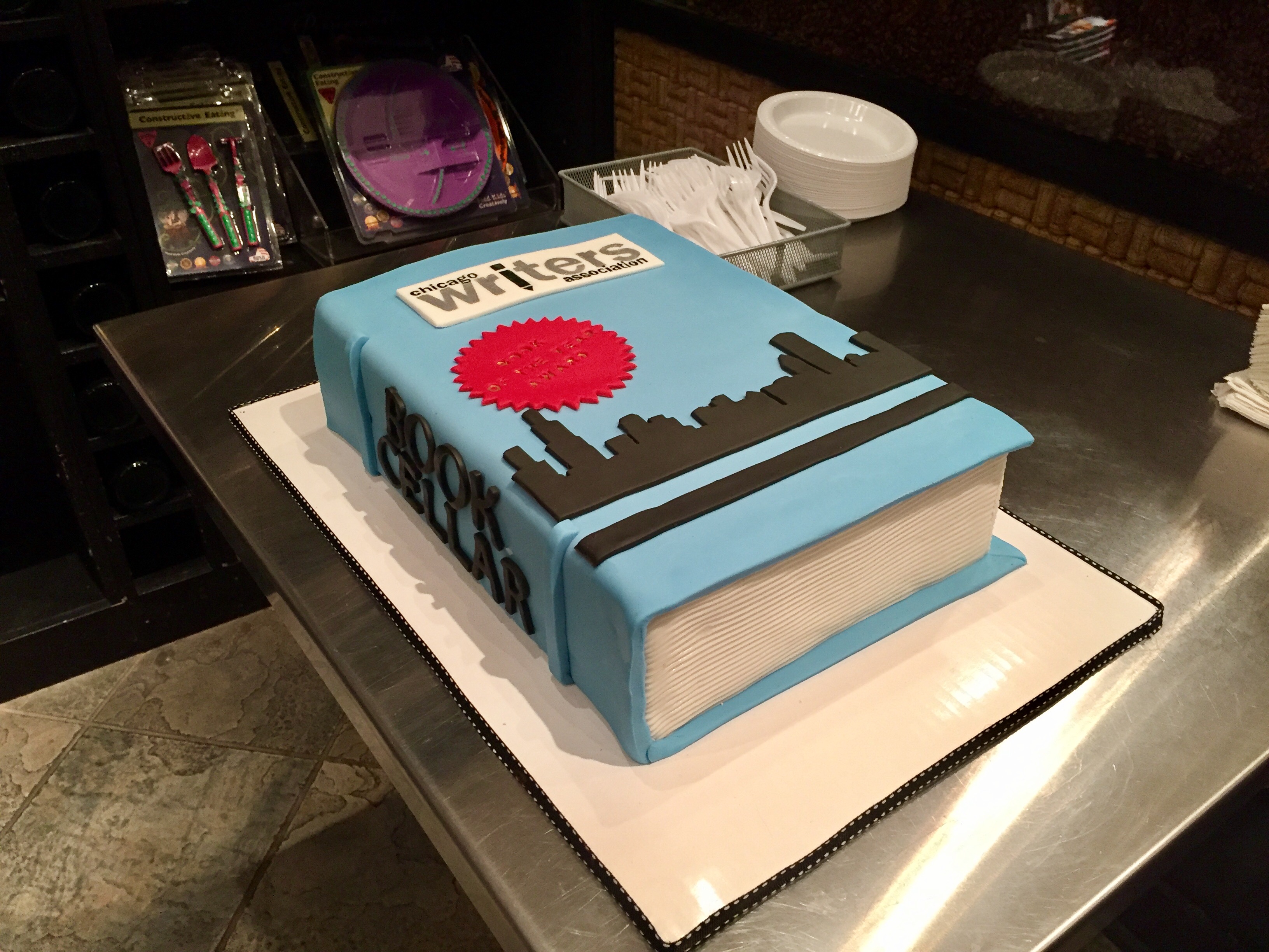 Cake in the shape of a book with the title of Chicago Writers Association